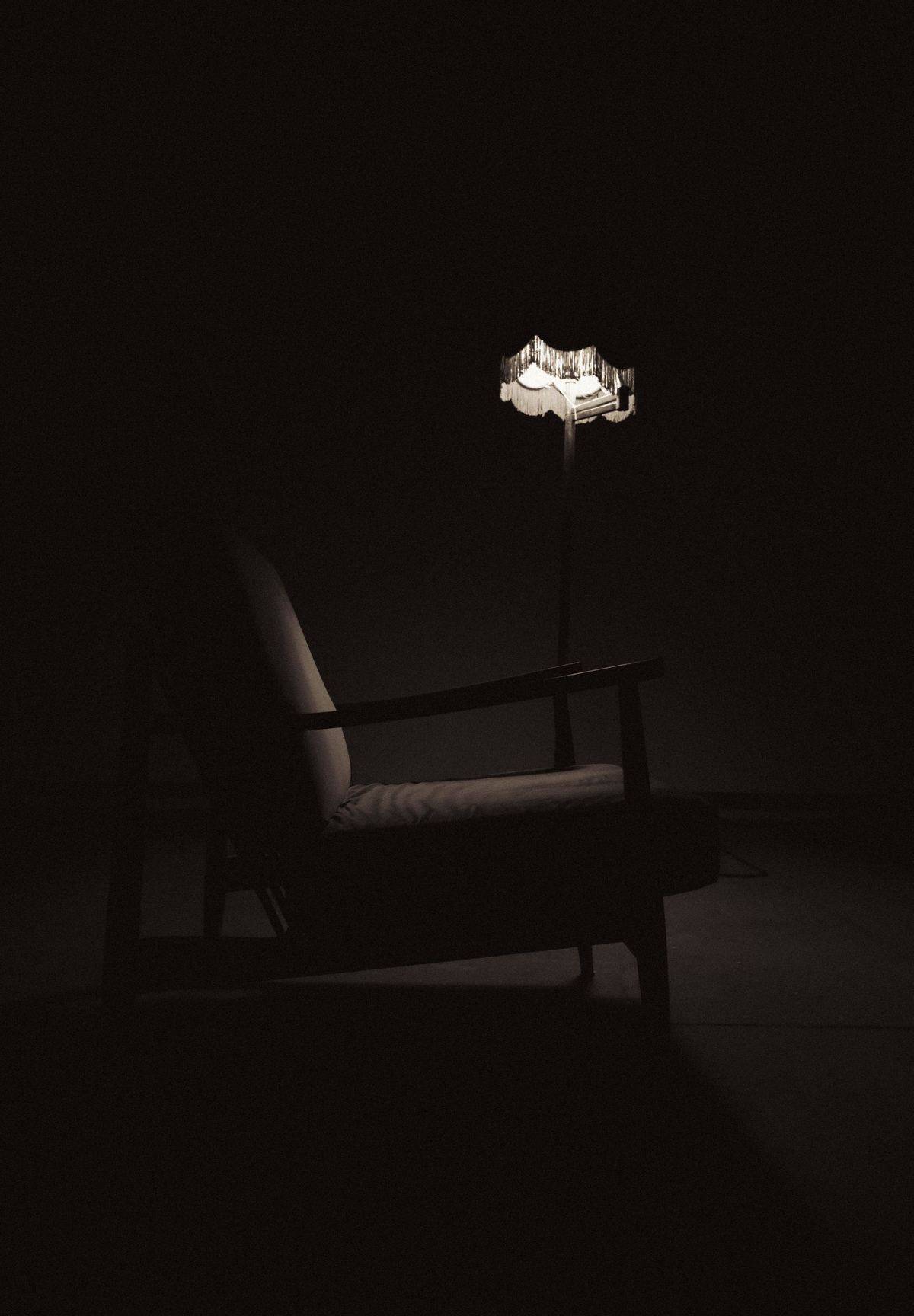 Poltrona sob a luz de uma luminária em sala escura